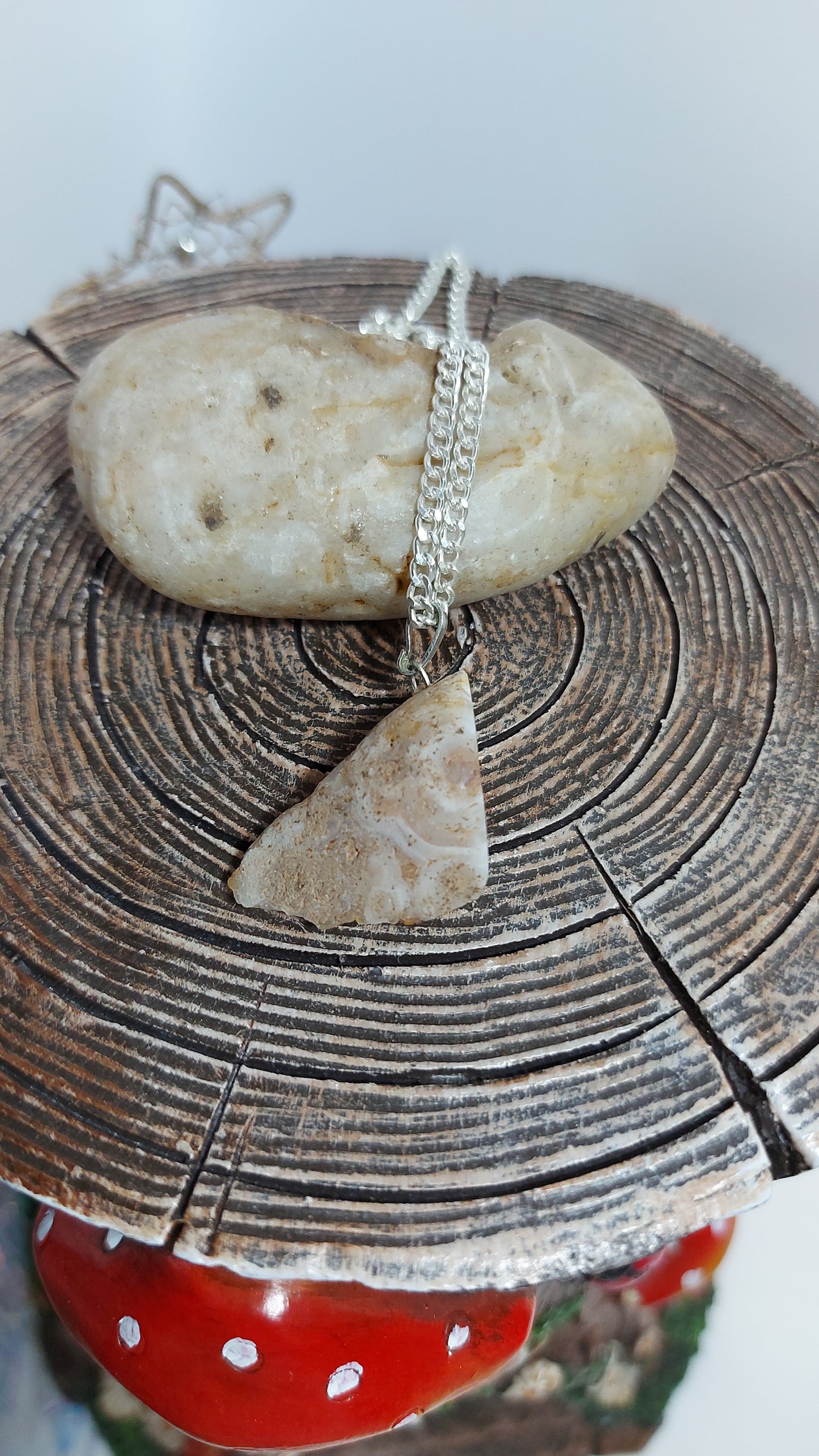 a small geode pendant on a silver necklace with rock photographed on afairy tree stump